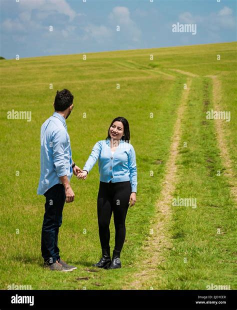 Beautiful couple holding hands looking at each other in the field, two ...