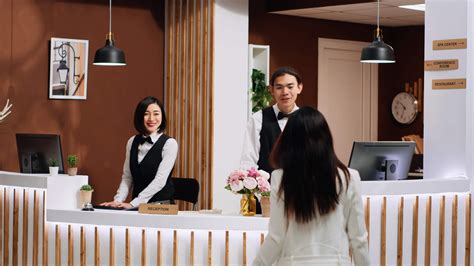 Front desk team staff welcoming hotel guest at reception, smiling and ...