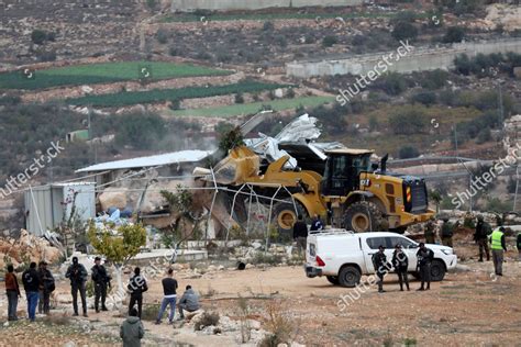 People watch an Israeli army bulldozer demolishing homes in the Palestinian urban refugee camp of Nu