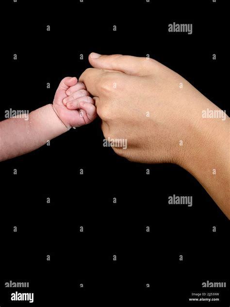 The hand of a caucasian newborn with a clenched fist bumps the knuckles ...