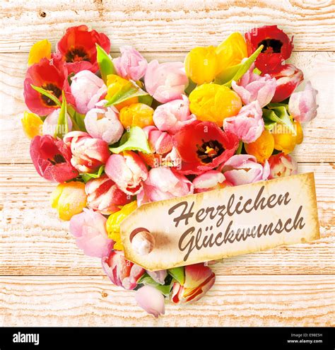 German birthday wishes on a colourful floral heart formed of fresh ...