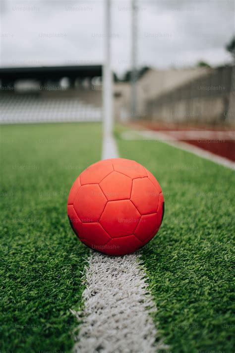 A red soccer ball sitting on top of a soccer field photo – Football ...
