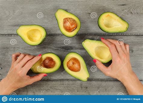 Tabletop View, Woman Hands with Red Nails Holding Avocados Cut in Half ...