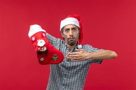 Front view of young man wearing christmas sock on red wall | Free Photo