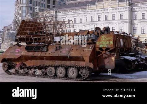 A man walks past a burnt armoured personnel carrier near buildings destroyed in the course of Ukrain