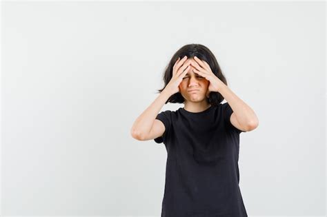 Little girl holding hands to face in black t-shirt and looking ...