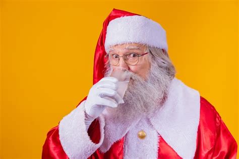 Santa claus drinking a glass of water on yellow background with space ...
