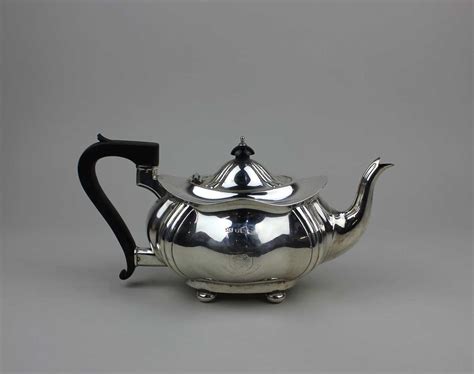 An Edward VII tea pot of oval form with fluted corners, a hinged dome ...