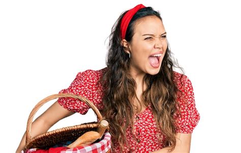 Jong spaans meisje met picknick rieten mand met brood boos en boos ...