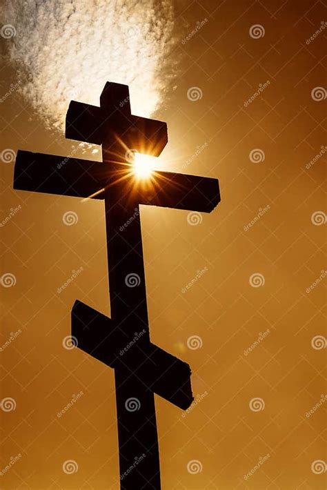 Orthodox Christian Wooden Cross Against Orange Sky and Sun Rays through ...