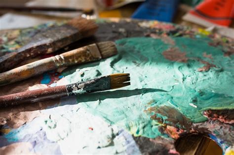 Close-up of colorful messy old paint brush and palette | Free Photo