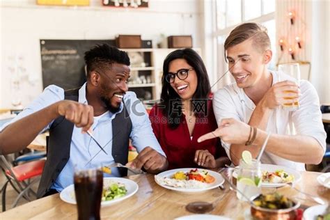 休闲、美食和人的概念-一群快乐的国际朋友在餐桌上吃饭和玩乐。高清摄影大图-千库网