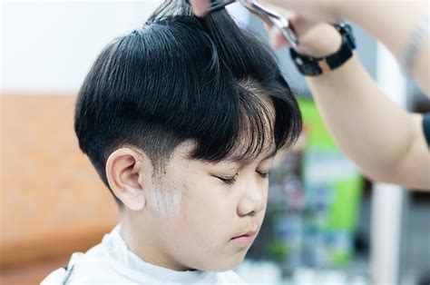 Asian boy is cut his hair in barber shop - people in hairdresser beauty ...
