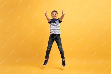 Premium Photo | Cute happy kid boy jumping up showing thumb ups