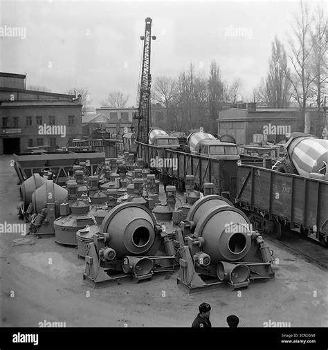 Newly manufactured concrete mixer trucks are loaded onto open railway cars for shipment, while ... - distribution of output in planned economy