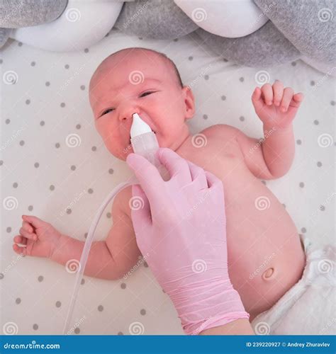 The Doctor Removes a Runny Nose with a Suction Device in a Newborn Baby. Nurse in Uniform Treats ...