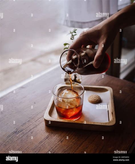 Hand pouring coffee cold brew espresso ice coffee with ice cubes. Glass ...