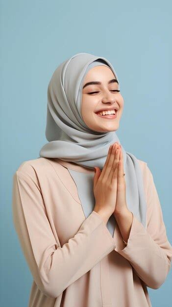Southeast asian woman wearing scarf is praying and smiling on blue ...
