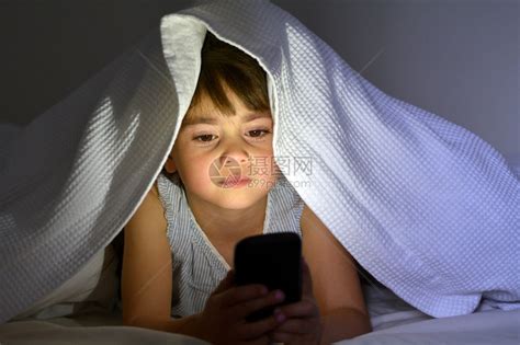 小孩56岁女孩晚上在床底下的床上用智能电话玩前高清图片下载-正版图片502908241-摄图网