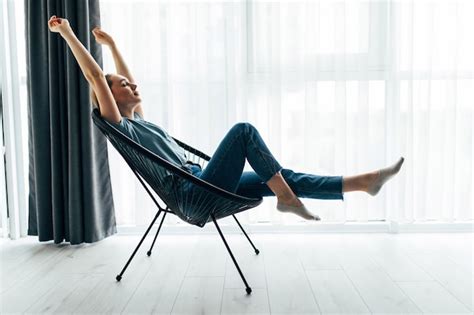 Young pretty woman at home sitting on modern chair in front of window ...