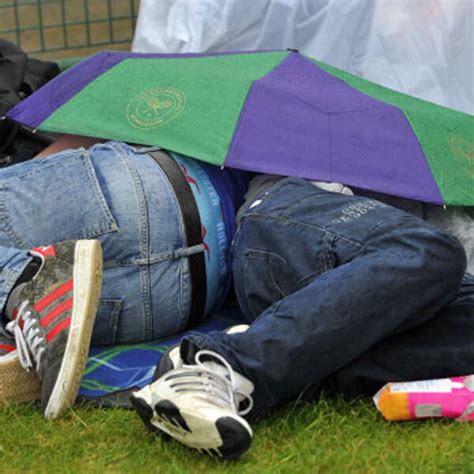 Spectators shelter under an umbrella on the grass at Murray Mount as ...