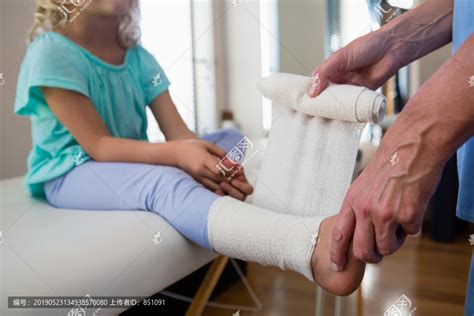 理疗师在女患者受伤的脚上缠绷带,摄影素材,汇图网www.huitu.com