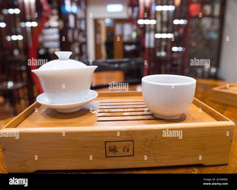 Gong Fu Cha brewing. Beautiful white porcelain (Gaibei/ Gaiwan & tea cup) set on a bamboo tray ...