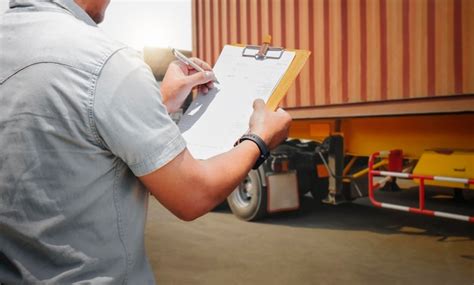 Worker holds a clipboard controlling the loading of cargo into shipping ...