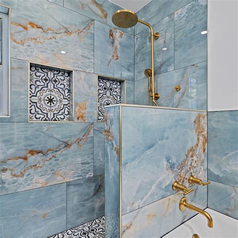 a bathroom with blue marble tile and gold faucet shower head in the corner