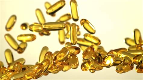 Omega 3 vitamin capsules rise and fall. On a gray background. Filmed is slow motion 1000 fps ...