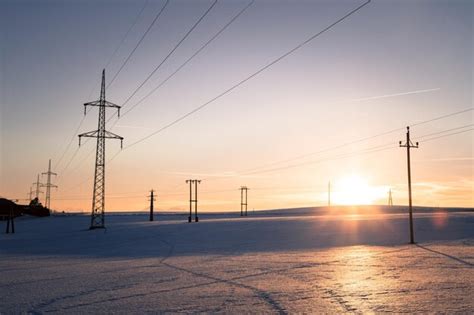 Torre elétrica em um campo de neve sol desce cenário noturno de cores ...