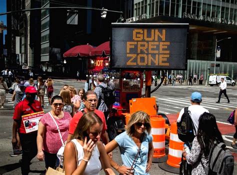 New York :Passersby walk past gun-free zone signages near Times Square ...