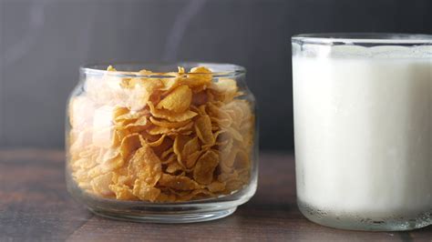 Corn flake cereal and milk in separate containers on table 13124758 ...
