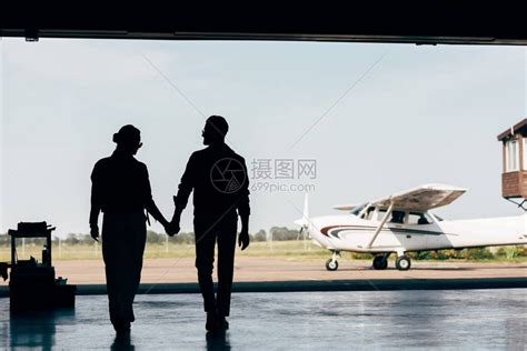 年轻夫妇手牵在飞机附近停在机库行走高清图片下载-正版图片503355299-摄图网