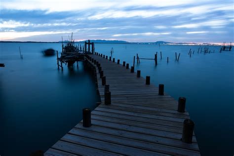 Jetée sur la mer entourée de collines sous un ciel nuageux dans la ...