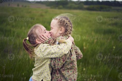 two sisters hug and kiss in the field 45641853 Stock Photo at Vecteezy