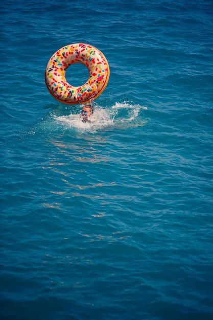 Jonge vrouw drijvend op een opblaasbare grote donut in de transparante ...