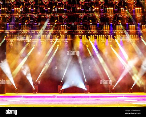 Illuminated empty concert stage with haze and rays of pink and yellow ...