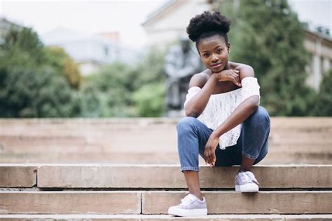 Afroamerikanerfrau, die auf Treppe durch die Universität sitzt ...