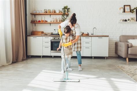 Eine kleine Tochter und ihre Mutter putzen das Haus, ein Kind wäscht ...