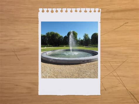 A brick factory stands in front of a park, with open green space, a reflecting pool, and benches