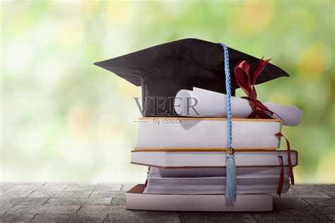 毕业帽与学位论文放在一堆书上照片摄影图片_ID:141144572-Veer图库