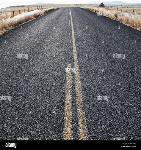 Two Lane Road Between Fenced Fields Stock Photo - Alamy