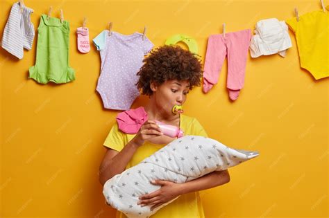 Young caring mother holds infant son wrapped in duvet on hands, feeds ...
