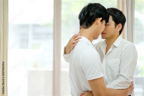 Asian gay couple with white shirt kiss together in bed room with day ...