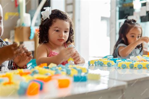 Niña hispana de preescolar jugando con bloques de colores en un jardín ...