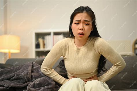 Premium Photo | Unhappy young woman holding belly suffering from ...