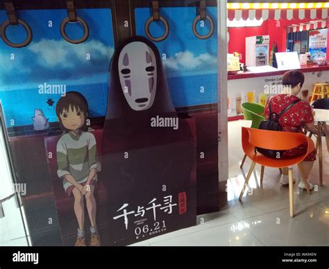 --FILE--A filmgoer waits beside a poster of Japanese animated film ...