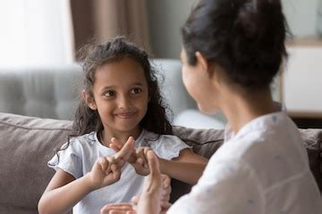 Happy cute indian kid girl talking to mother using hands fingers ...