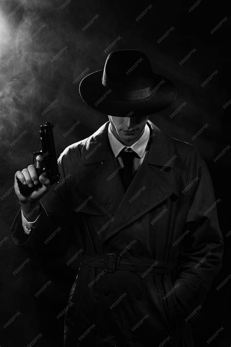 Premium Photo | A dark silhouette of a male detective in a coat and hat with a gun in his hands ...